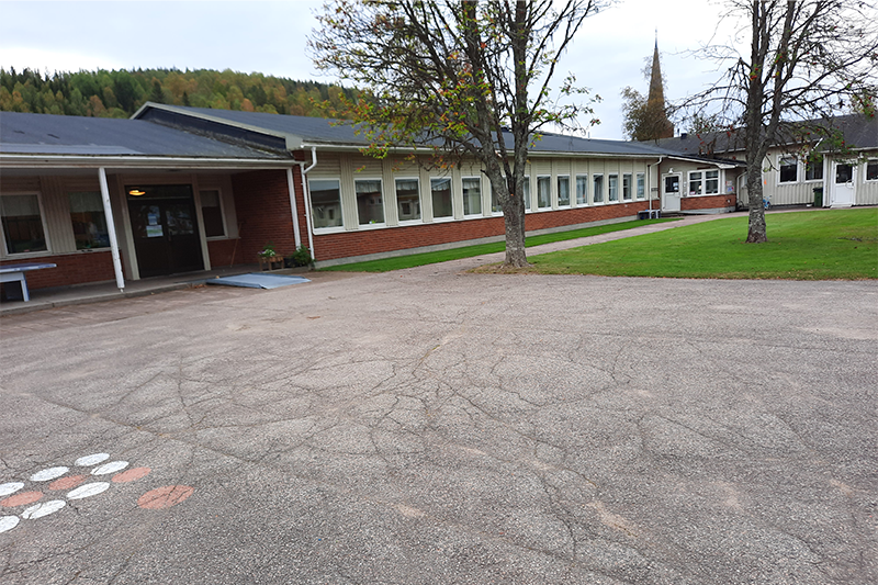Bilden visar en skolgård med bollplan av asfalt. 