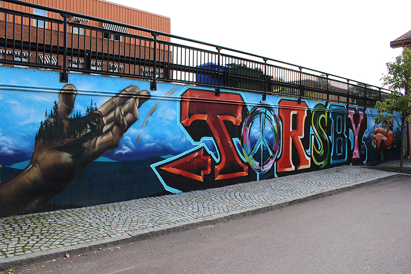Namnet Torsby är målat med stora bokstäver i klara färger på en mur.