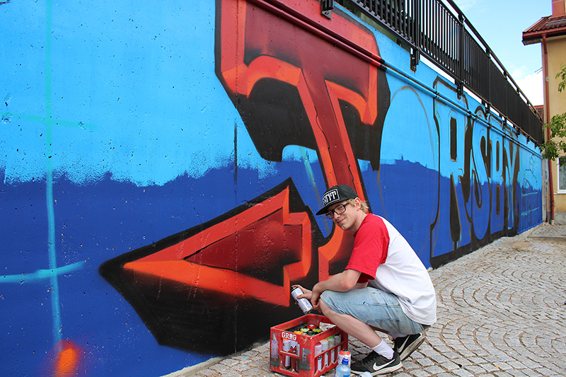 En man står böjd och målar på en mur.